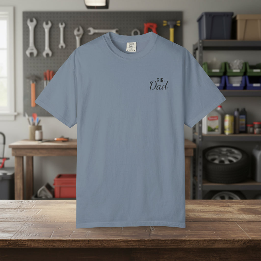Blue t-shirt with 'Girl Dad' text on a wooden table in a workshop setting