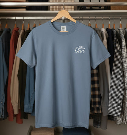 Blue t-shirt with 'Girl Dad' text on a hanger in a clothing store.
