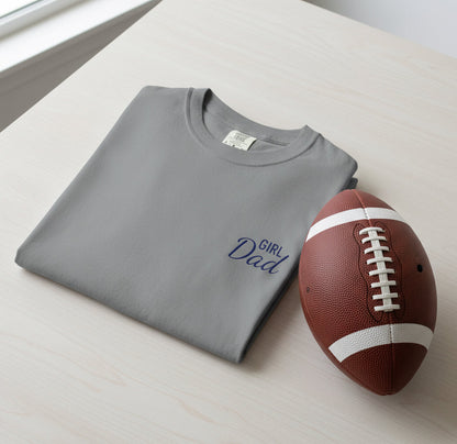 Gray t-shirt with 'Girl Dad' text and a football on a light surface