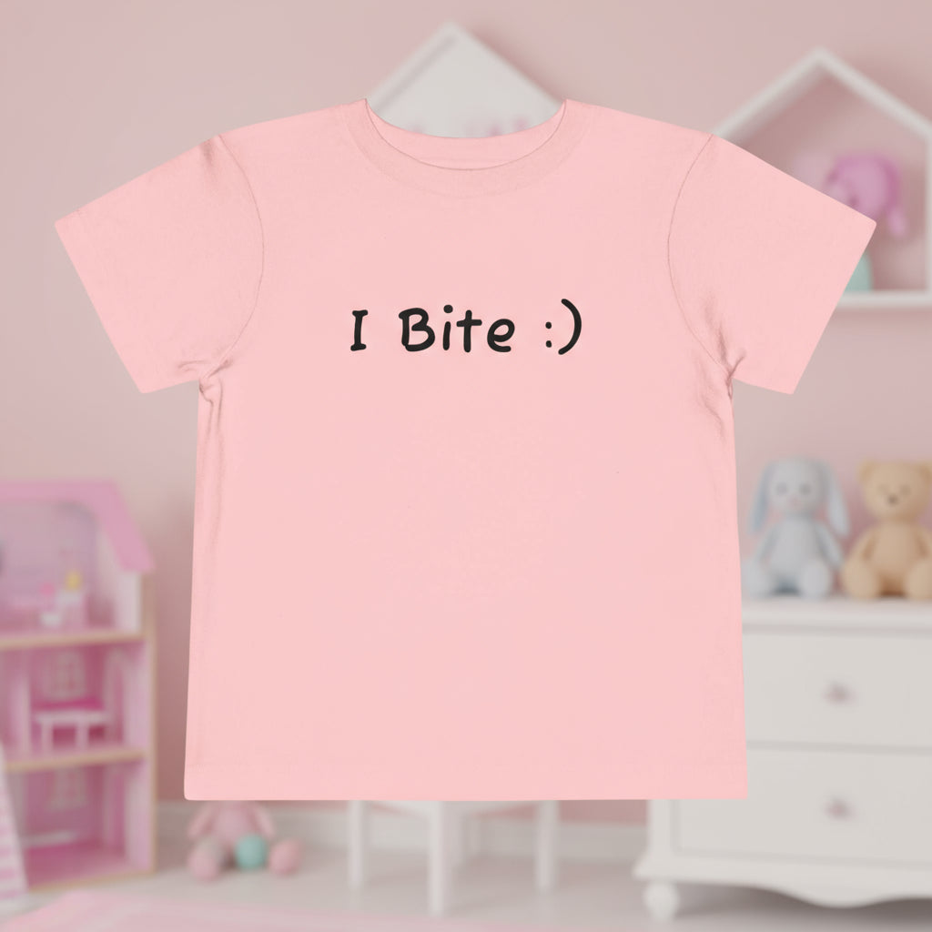 Pink t-shirt with 'I Bite :)' text in a child's room.