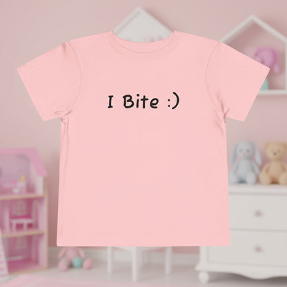 Pink t-shirt with 'I Bite :)' text in a child's room.